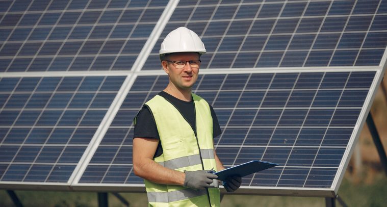 Engineer in a white helmet. Man near solar panel. Worker with a folder.